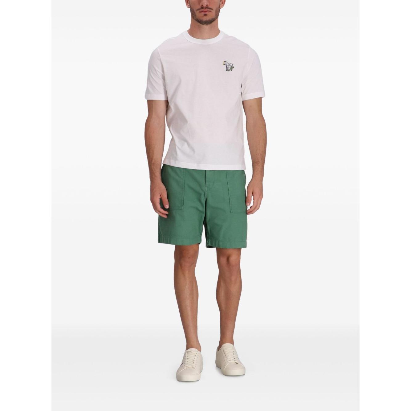 Model wearing PS By Paul Smith white cotton t-shirt with zebra logo, green shorts, and white sneakers. Short sleeve crew neck style.