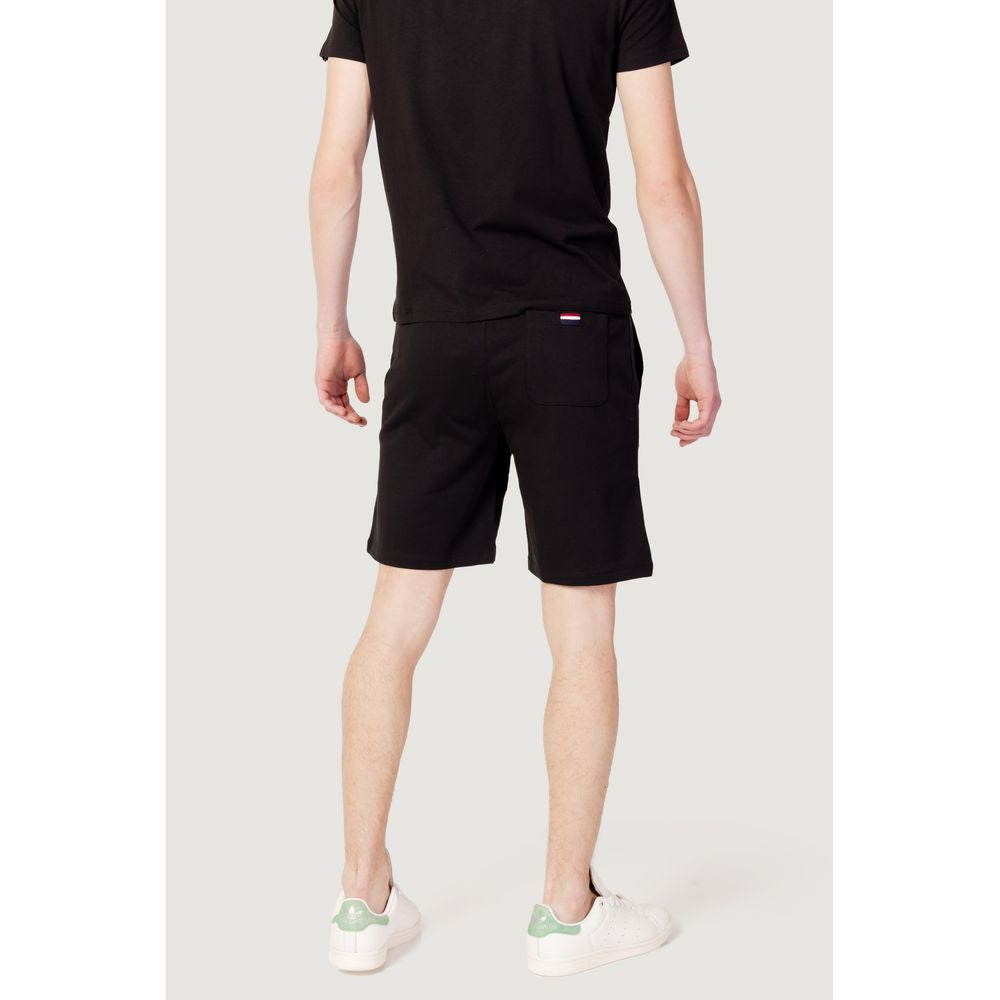 Back view of model wearing U.S. POLO ASSN. black cotton Bermuda shorts, spring/summer collection, paired with white sneakers.