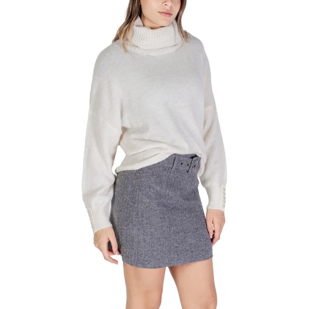 Woman wearing ICHI cream acrylic turtleneck sweater paired with grey skirt, ideal for women's fall and winter knitwear fashion.