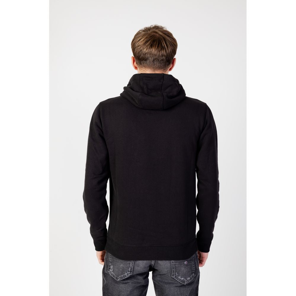 Back view of a man wearing a black Tommy Hilfiger organic cotton men's hoodie from the Fall/Winter collection.