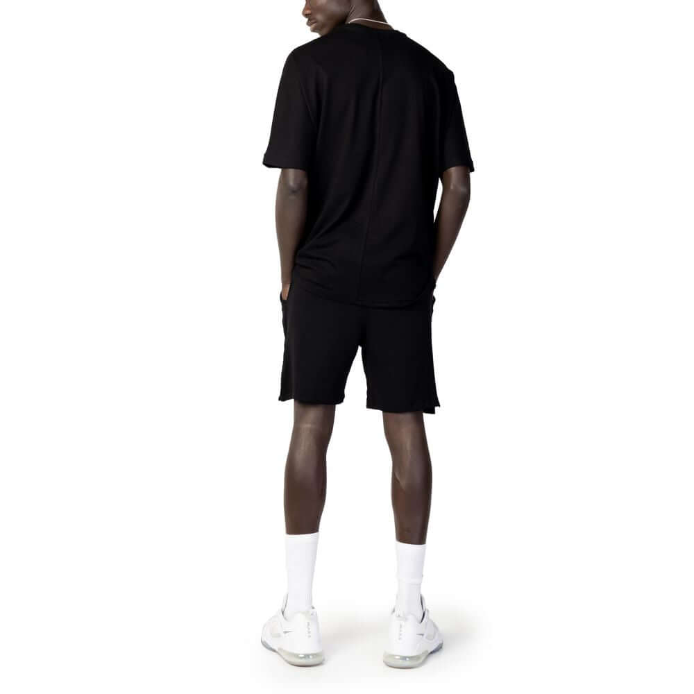 Back view of a man wearing a Hydra Clothing black cotton men's short suit from the spring/summer collection, featuring a casual design.