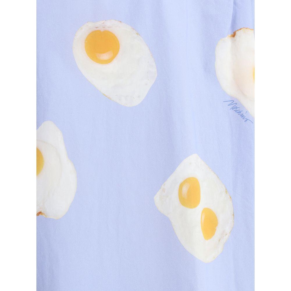 Moschino printed shirt with all-over egg graphic on a light blue background, showcasing playful and creative fashion design.