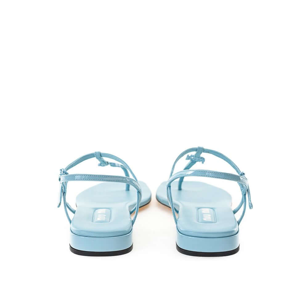 Back view of Miu Miu blue patent leather thong sandal with T-style strap, square toe, and contrasting black under heel.