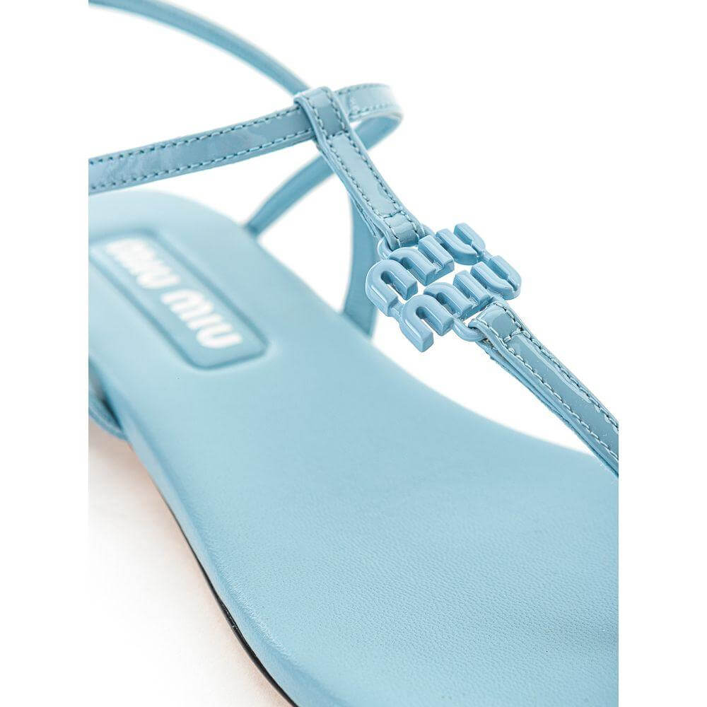 Close-up of Miu Miu blue patent leather sandal with square toe, T-style design, and logo lettering, highlighting the fine leather finish.