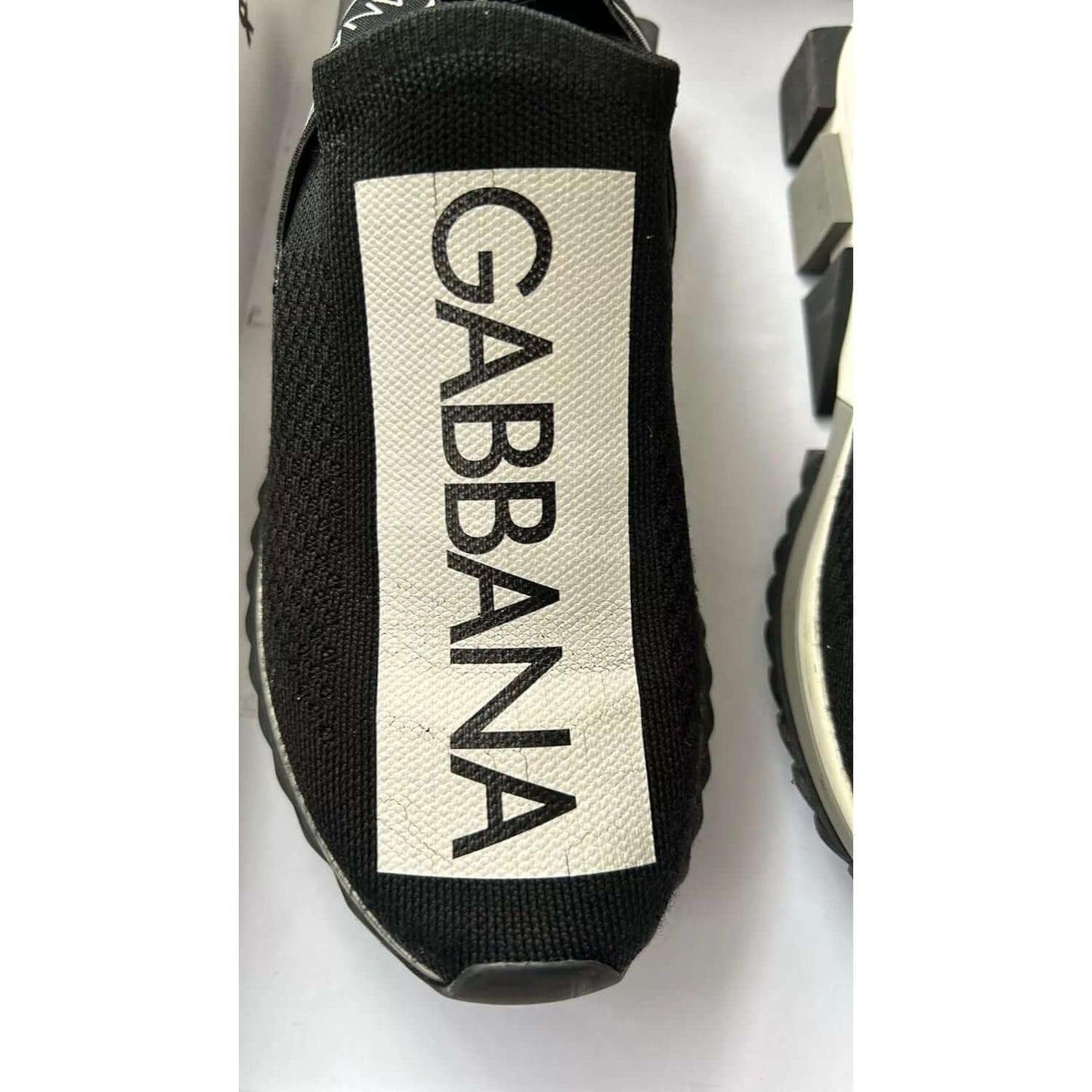 Dolce & Gabbana Sorrento black and white slip-on sneaker with logo print and rubber sole, close-up view.