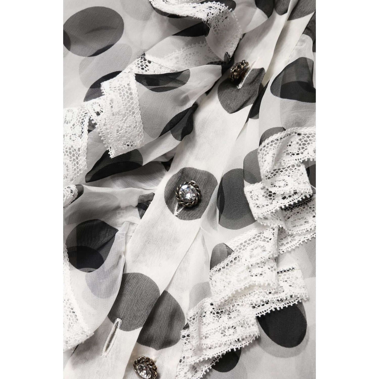 Close-up of Dolce & Gabbana white and black polka dot silk blend sleeveless top with lace trim and button details, made in Italy.