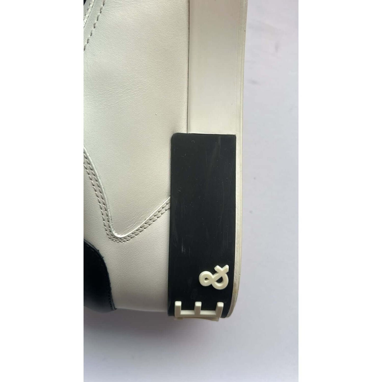 Close-up of Dolce & Gabbana Portofino white leather sneaker with logo detail, black rubber sole, high craftsmanship, preowned condition
