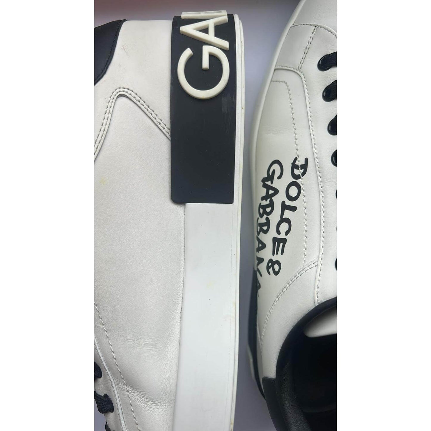 Dolce & Gabbana Portofino white leather sneakers featuring logo and rubber sole, showing minor wear marks. Lace-up design, Italian craftsmanship.